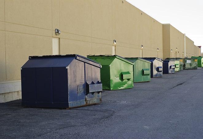 tilted front-load dumpsters being emptied by waste management workers in Fackler